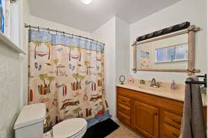 Bathroom with vanity, walk in shower, a textured ceiling, tile patterned flooring, and toilet