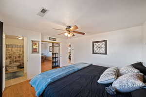 Bedroom with ceiling fan, ensuite bath, wood-type flooring, and a textured ceiling