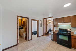 Kitchen featuring a fireplace, electric range, and backsplash