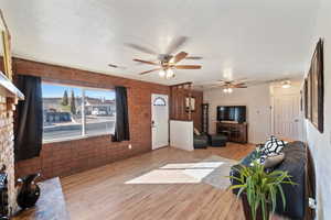 Living room featuring light hardwood / wood-style flooring, brick wall, and a textured ceiling