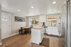 Kitchen with white cabinets, appliances with stainless steel finishes, butcher block countertops, and a kitchen island