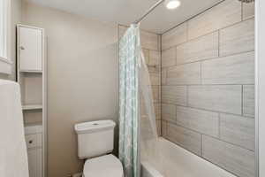 Bathroom featuring shower / tub combo with curtain and toilet