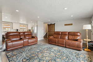 Living room featuring hardwood / wood-style flooring, sink, a barn door, and a textured ceiling