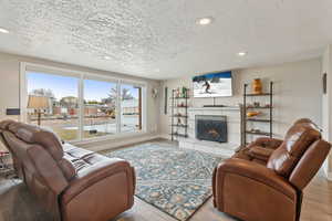 Living room featuring a tile fireplace, a textured ceiling, and light hardwood / wood-style floors