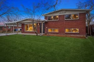 View of front of property featuring concrete driveway, a lawn, a carport, and brick siding