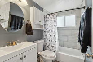 Full bathroom with toilet, vanity, and shower / bath combination with curtain