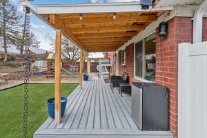 Wooden terrace with a playground and a lawn