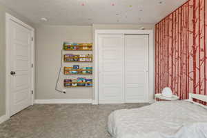 Bedroom with carpet floors, a textured ceiling, and a closet