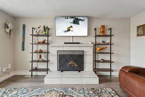 Living room with a fireplace, a textured ceiling, and wood-type flooring