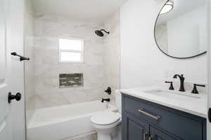 Full bathroom with toilet, vanity, and tiled shower / bath