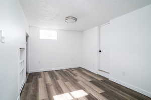 Unfurnished room with a textured ceiling and dark hardwood / wood-style flooring