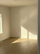 Spare room featuring wood finished floors, baseboards, and visible vents