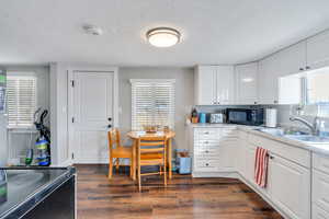 Kitchen with white cabinetry, dark wood-type flooring, sink, and black appliances