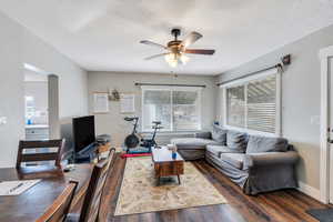 Living room featuring ceiling fan, dark wood-type flooring, and a textured ceiling