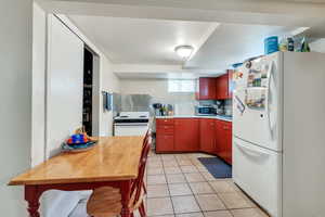 Kitchen featuring light tile patterned floors, white appliances, and tasteful backsplash