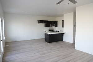 Kitchen featuring a breakfast bar area, stainless steel appliances, kitchen peninsula, ceiling fan, and light hardwood / wood-style flooring