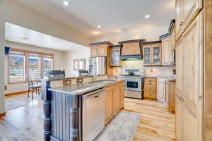 Kitchen featuring sink, appliances with stainless steel finishes, light stone countertops, a kitchen island with sink, and backsplash