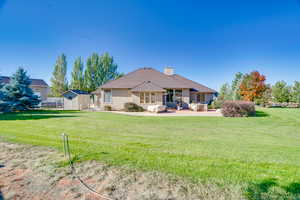 Back of house featuring a yard, a patio, and a storage unit