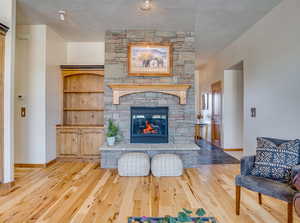 Living room with a textured ceiling, light wood-type flooring, and a fireplace