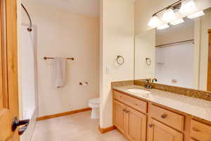 Full bathroom featuring vanity, bathing tub / shower combination, tile patterned floors, and toilet