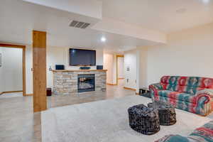 Tiled living room featuring a stone fireplace