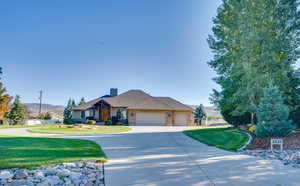 Ranch-style home featuring a garage, a mountain view, and a front yard