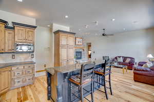 Kitchen with stainless steel microwave, a kitchen bar, decorative backsplash, light stone countertops, and a center island with sink