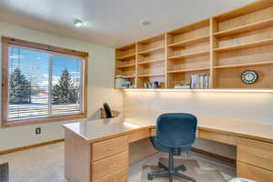 Carpeted home office featuring built in desk and a textured ceiling