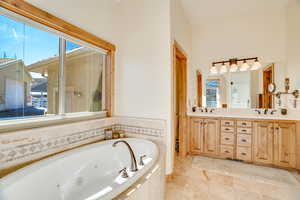 Bathroom with vanity, plenty of natural light, and tiled bath