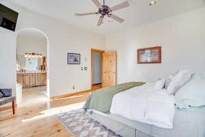 Bedroom featuring sink, connected bathroom, ceiling fan, and light hardwood / wood-style flooring