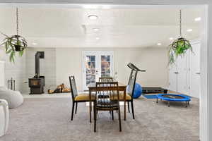 Carpeted dining area with a wood stove, french doors, and a textured ceiling