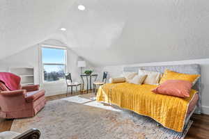 Bonus room with wood-type flooring, a textured ceiling, and lofted ceiling