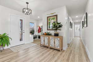 Entrance foyer with an inviting chandelier and light hardwood / wood-style flooring