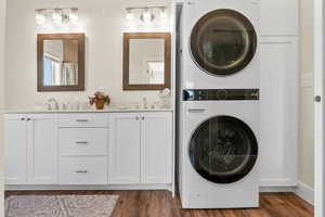 Laundry area featuring sink, stacked washer / dryer, and dark hardwood / wood-style floors