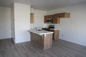 Kitchen with kitchen peninsula, appliances with stainless steel finishes, light hardwood / wood-style flooring, and sink