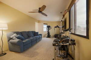 Living room featuring visible vents, a ceiling fan, and carpet floors