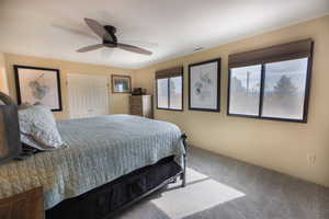 Bedroom with multiple windows, carpet flooring, a ceiling fan, and visible vents