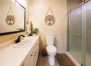 Full bathroom featuring vanity, an enclosed shower, toilet, and tile patterned flooring