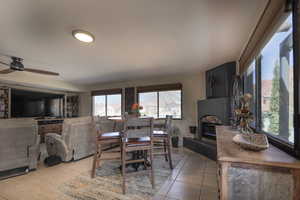 Dining room with a fireplace with raised hearth, ceiling fan, and light tile patterned flooring