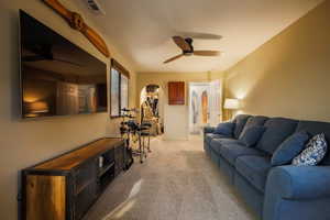 Living room featuring visible vents, light colored carpet, and ceiling fan