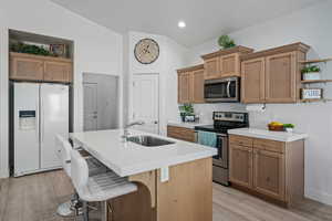 Kitchen featuring a kitchen breakfast bar, stainless steel appliances, an island with sink, light hardwood / wood-style floors, and sink