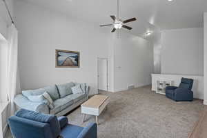 Carpeted living room featuring high vaulted ceiling and ceiling fan