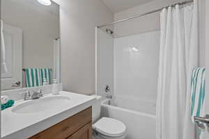 Full bathroom with shower / tub combo with curtain, toilet, and vanity