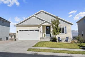 View of front of home featuring a mountain view, a front lawn, and a garage