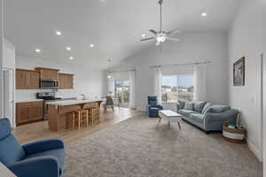 Living room with ceiling fan, light hardwood / wood-style flooring, sink, and high vaulted ceiling