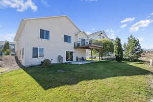 Rear view of property with a deck, a yard, and a patio area