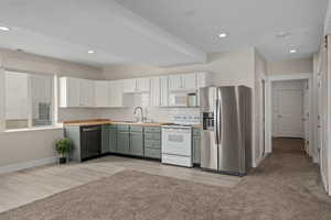 Kitchen featuring sink, white appliances, green cabinets, and decorative backsplash