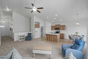 Living room featuring ceiling fan, high vaulted ceiling, and light colored carpet