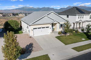 View of front of house featuring a mountain view, a front yard, and a garage