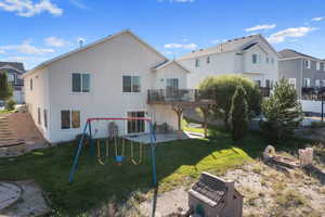 Rear view of property featuring a patio, a yard, a playground, and a balcony